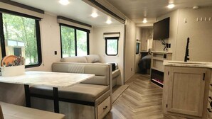 Een goed verlicht RV-interieur met een eethoek, zitplaatsen en een keuken.