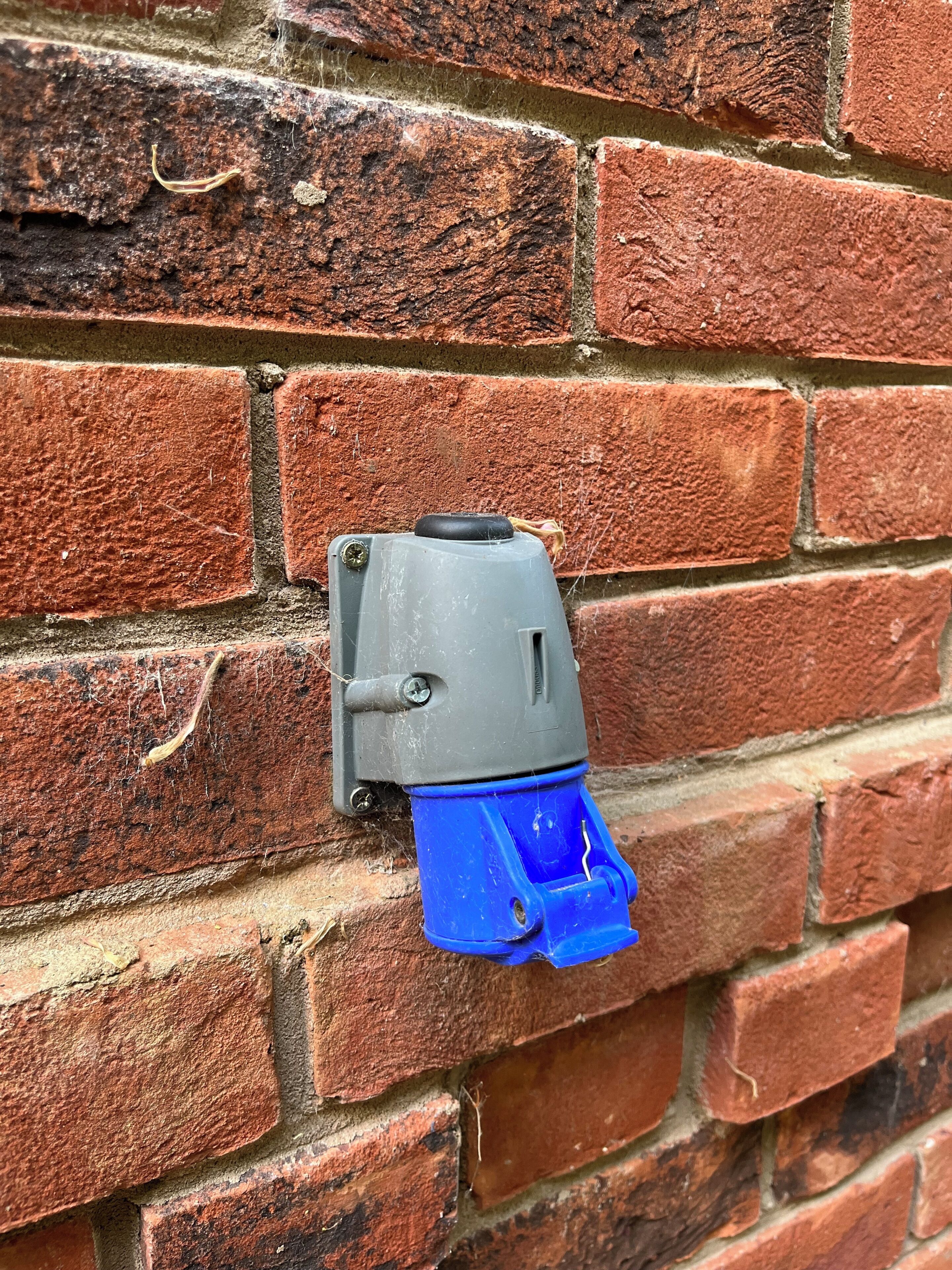 A wall-mounted electrical outlet on a brick wall.