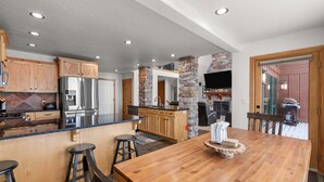 A spacious kitchen with a large island, wooden cabinets, and a stone accent wall. - Northwest Passage Retreat Ski-In/Ski-Out + Hot Tub (Sandpoint)