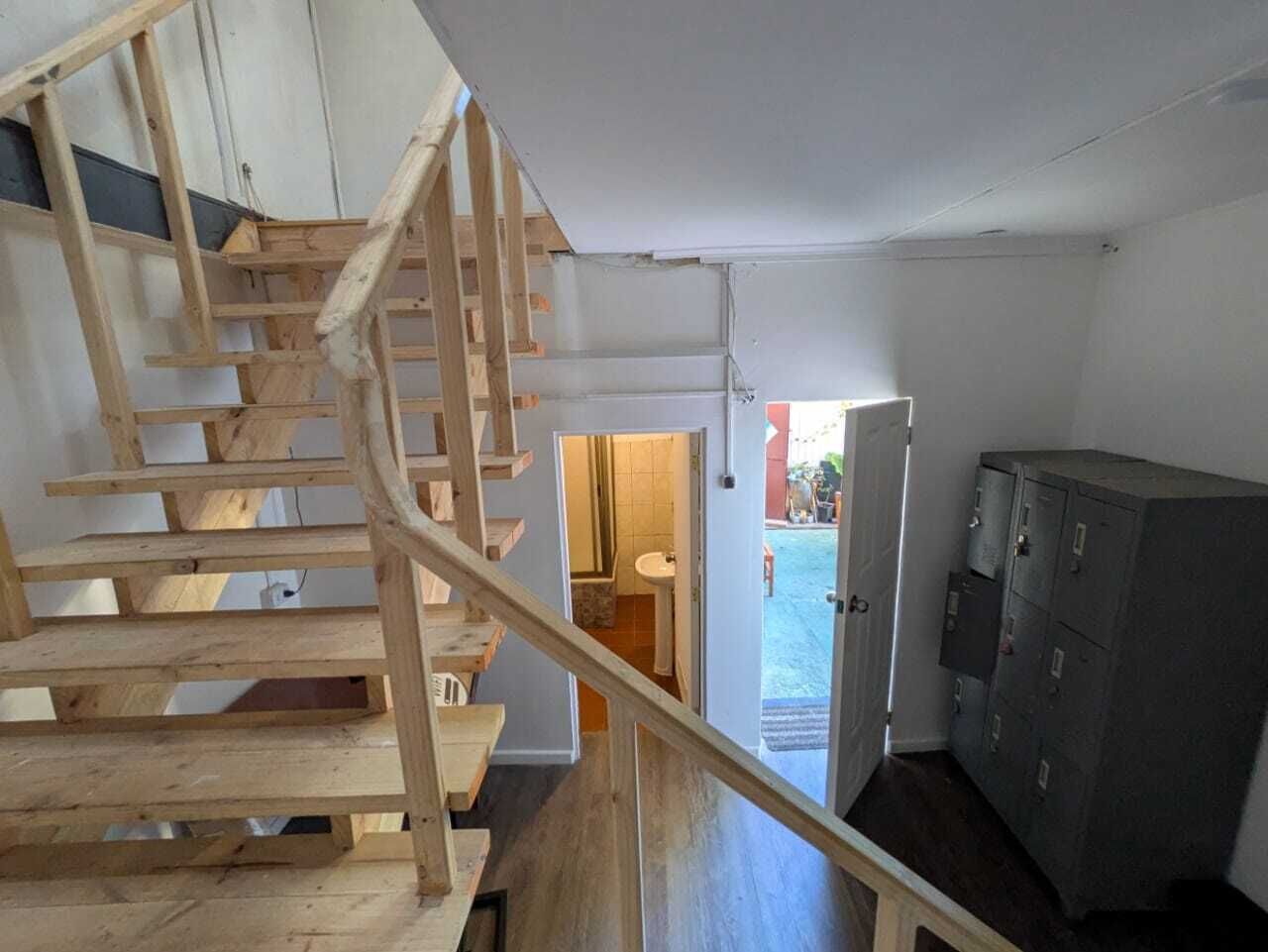 A wooden staircase leading to a bathroom with a sink and toilet visible through an open door.