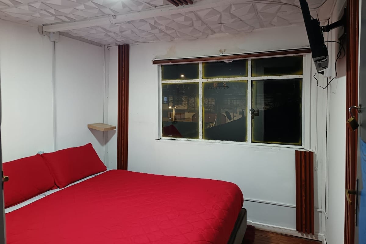 A room with a bed, a window, and a mounted television.