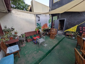 A courtyard with a green artificial turf, a wooden bench, a small table, and various potted plants.