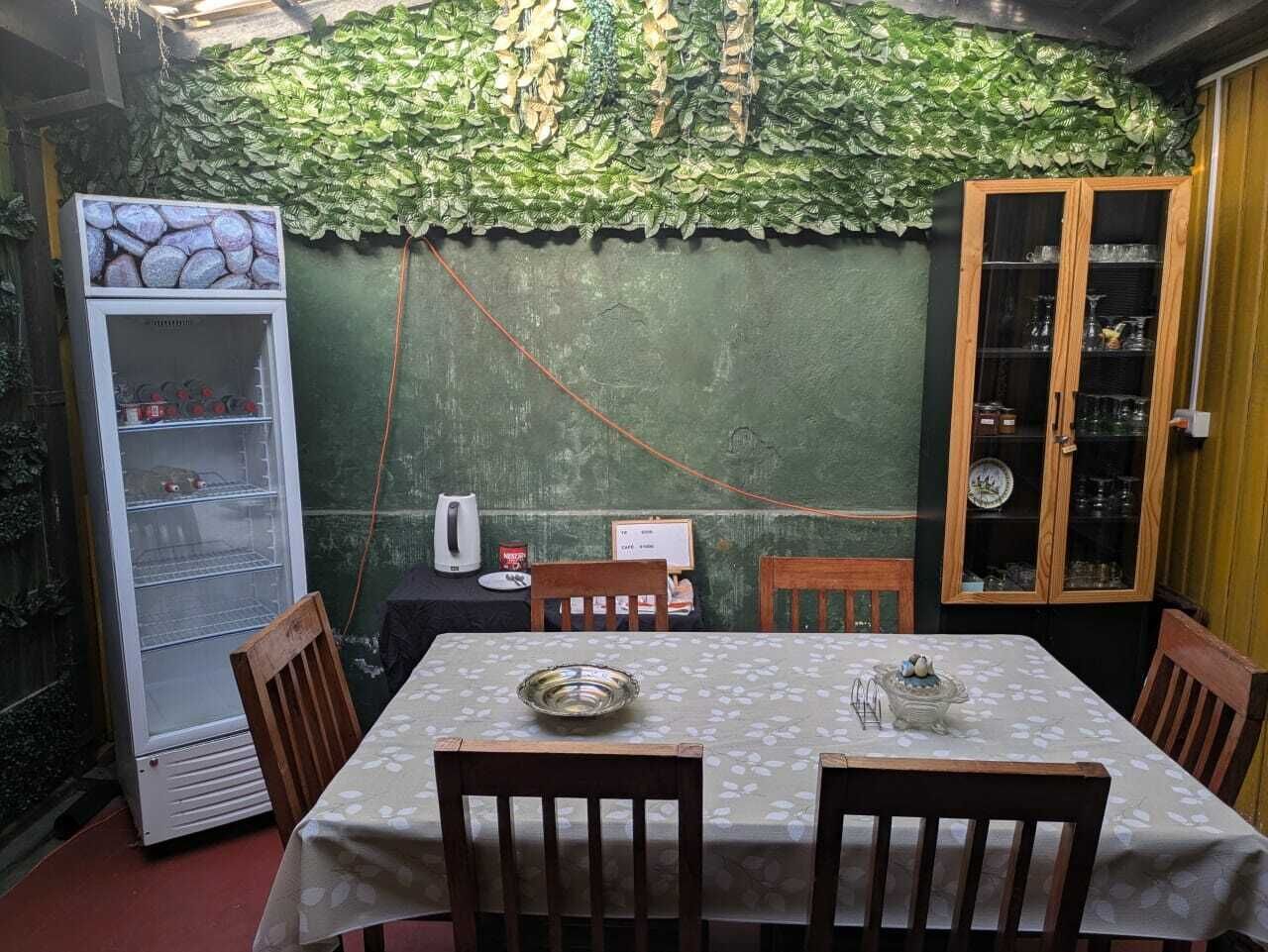 Ein Essbereich mit einem Tisch für zwei Personen, umgeben von Stühlen, einer Schrank mit Glastüren und einem Kühlschrank.