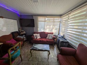 A living room with a red sofa, a coffee table, and a whiteboard with a list of items.