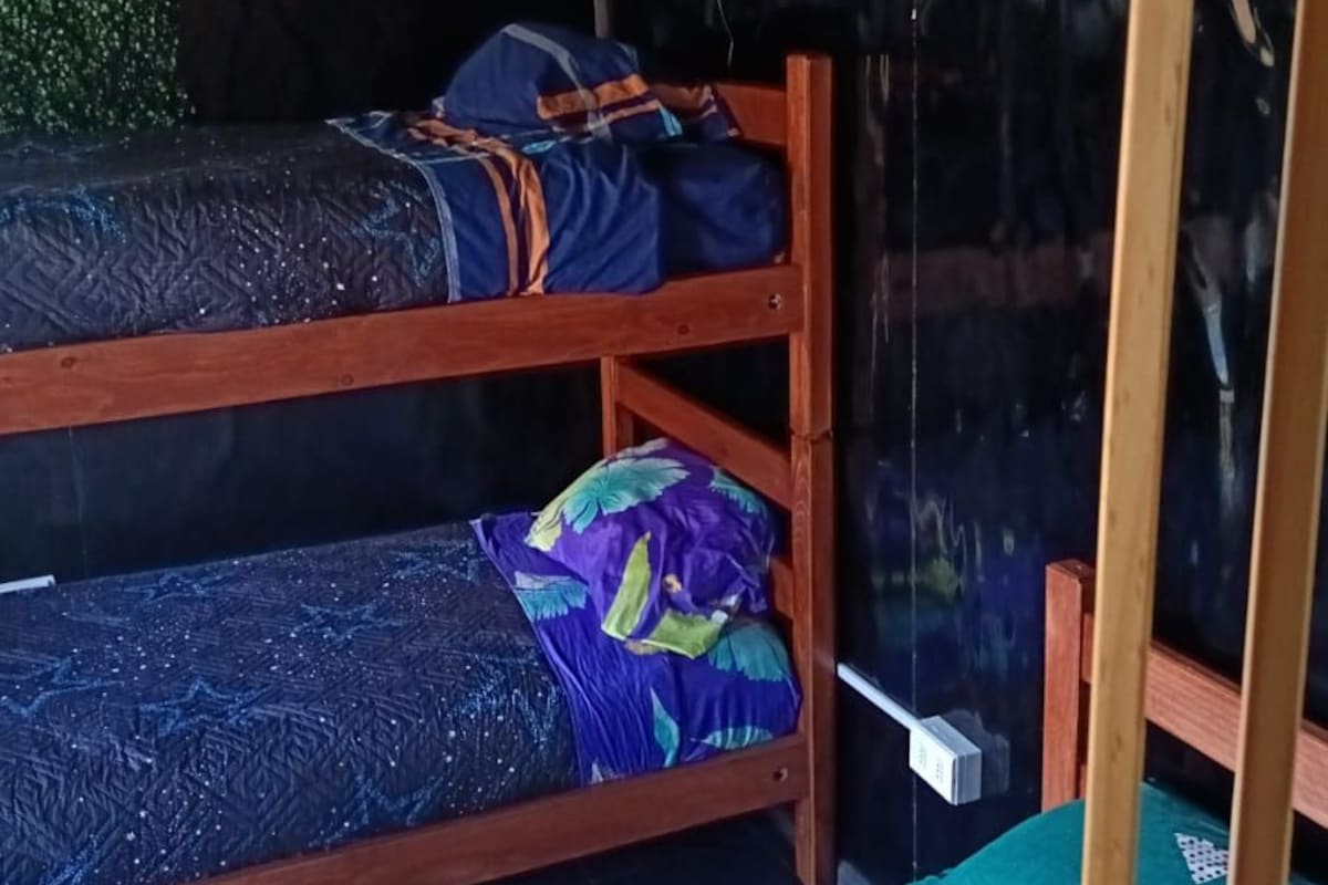 A bunk bed with a blue and purple patterned bedspread, a green and yellow pillow, and a no-smoking sign.