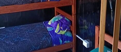 A bunk bed with a blue and purple patterned bedspread, a green and yellow pillow, and a no-smoking sign.