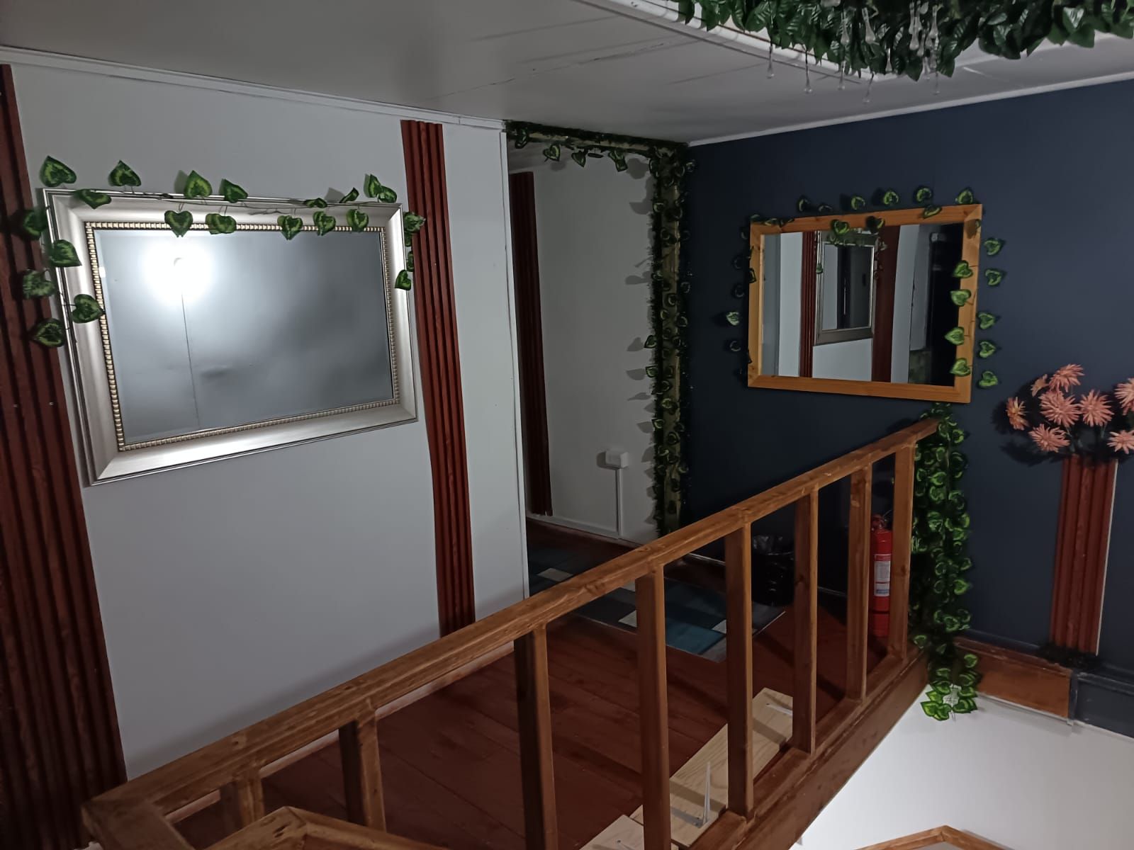 Un escalier avec des rampes en bois, un miroir et des éléments de décoration végétale.
