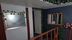 Una escalera con barandillas de madera, un espejo y plantas decorativas.