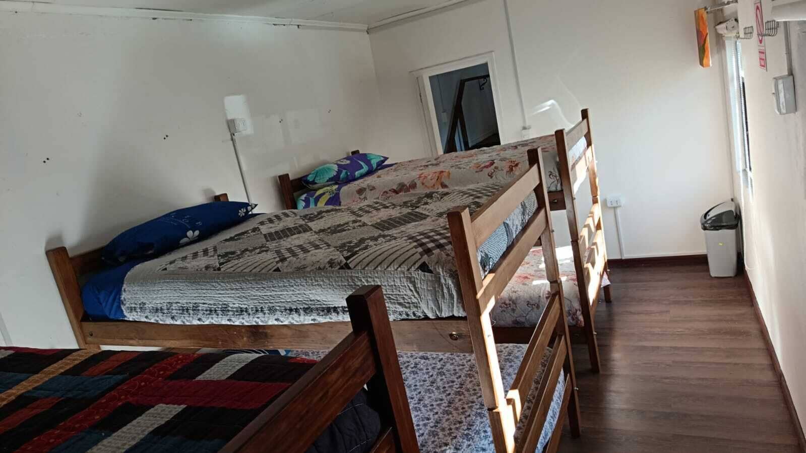 Una cama individual con estructura de madera, una colcha estampada y una almohada azul.