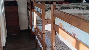 Un dormitorio con literas, un aparador de madera y una ventana.