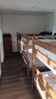 Un dormitorio con literas, un aparador de madera y una ventana.