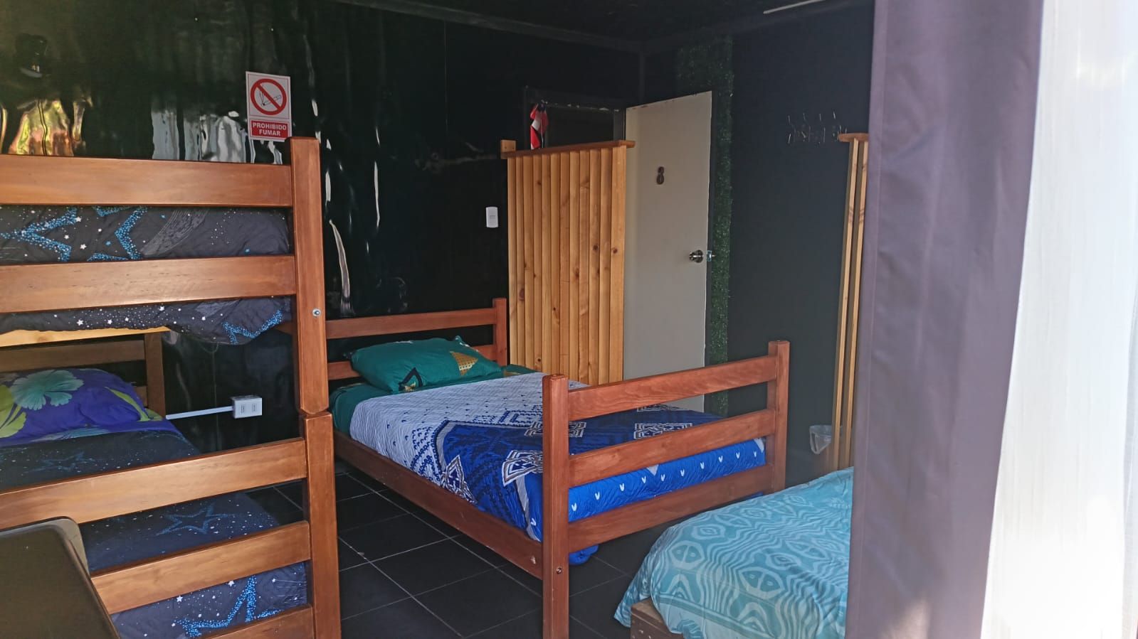 A room with bunk beds, a wooden wardrobe, and a door with a sign.