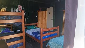 A room with bunk beds, a wooden wardrobe, and a door with a sign.