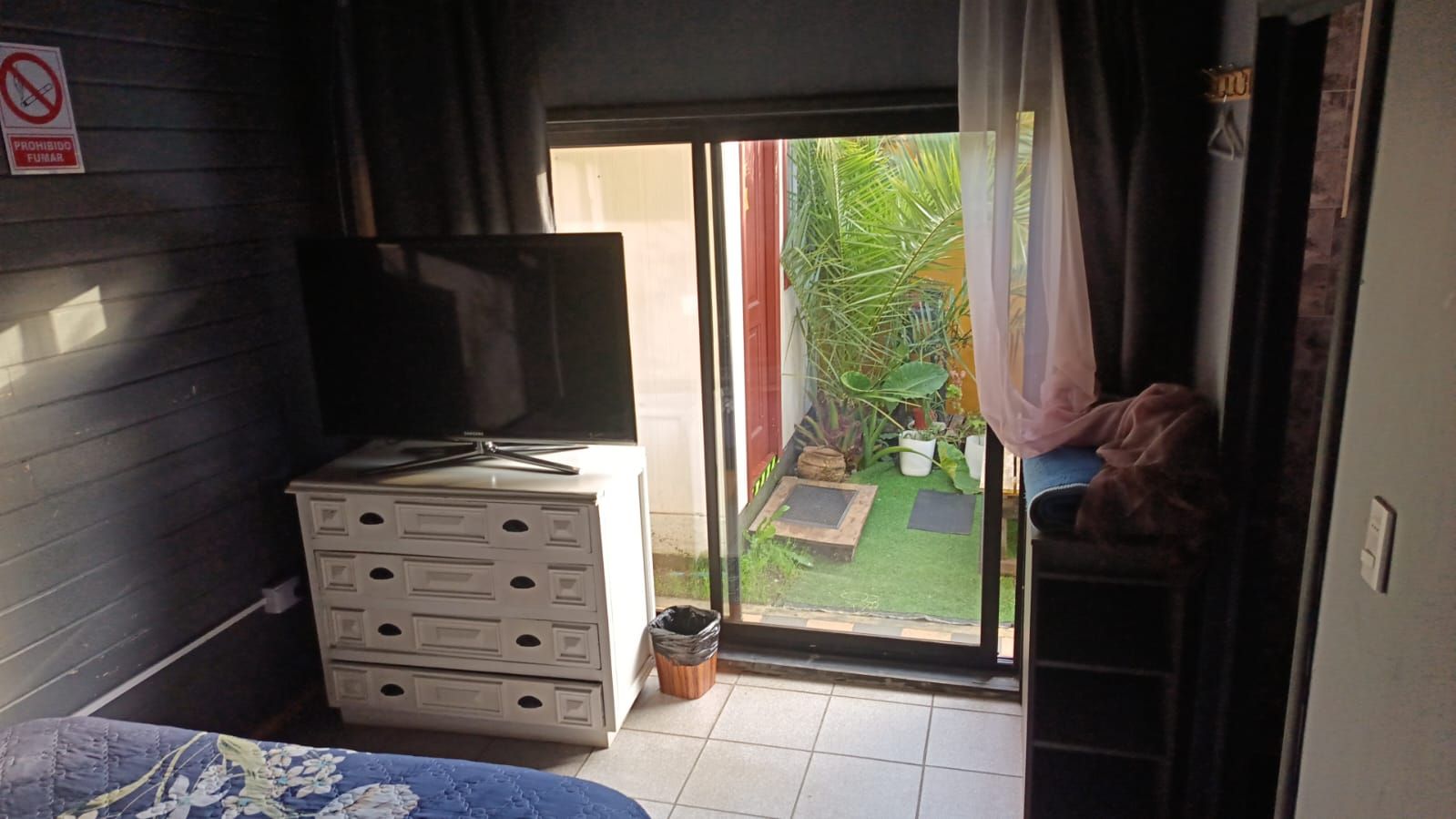 A room with a sliding glass door leading to a small outdoor area with plants.