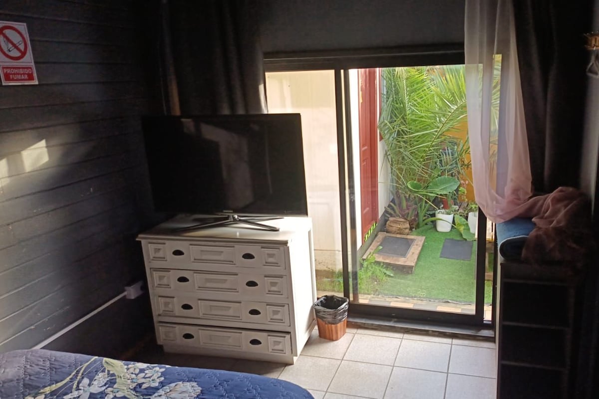 A room with a sliding glass door leading to a small outdoor area with plants.