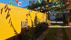 Pared amarilla con una escalera de madera y plantas en macetas. Banderines colgados encima.