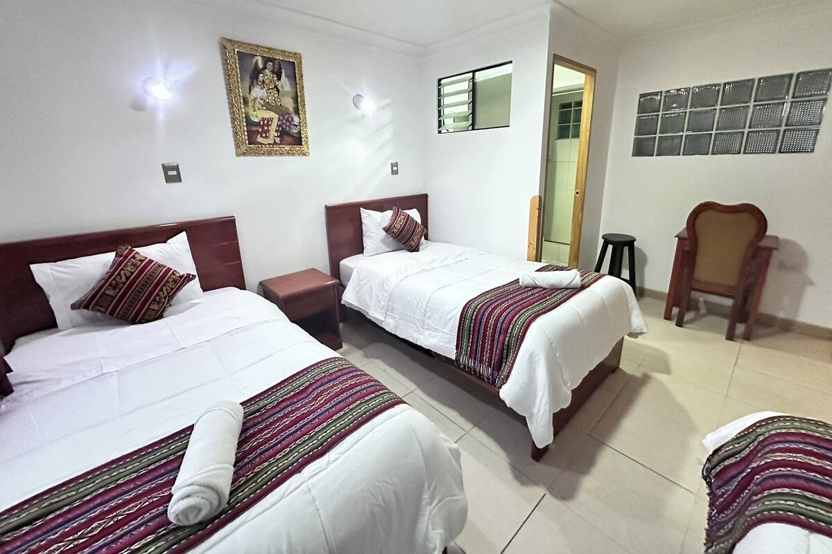 A hotel room with two beds, a nightstand, a chair, and a mirror.