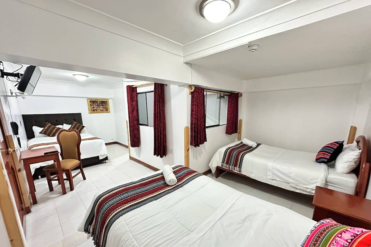 A hotel room with two beds, a desk, and a chair.