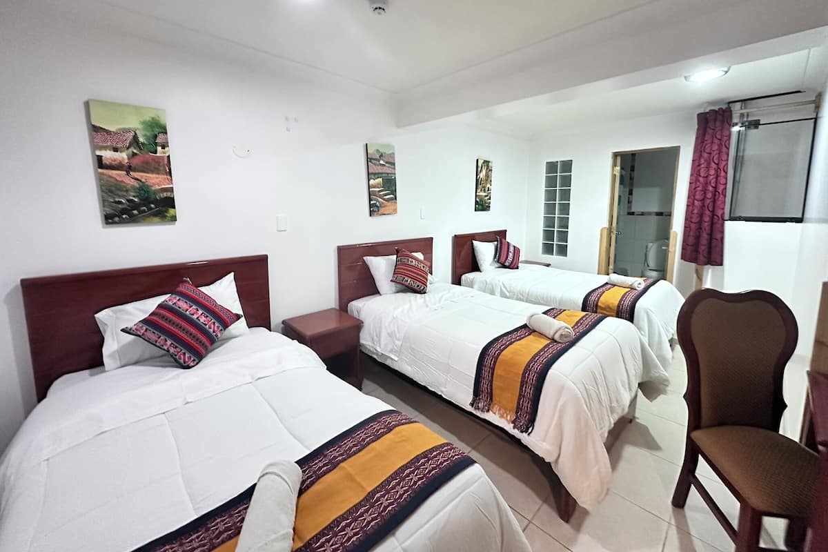 A hotel room with two beds, a chair, and artwork on the walls.