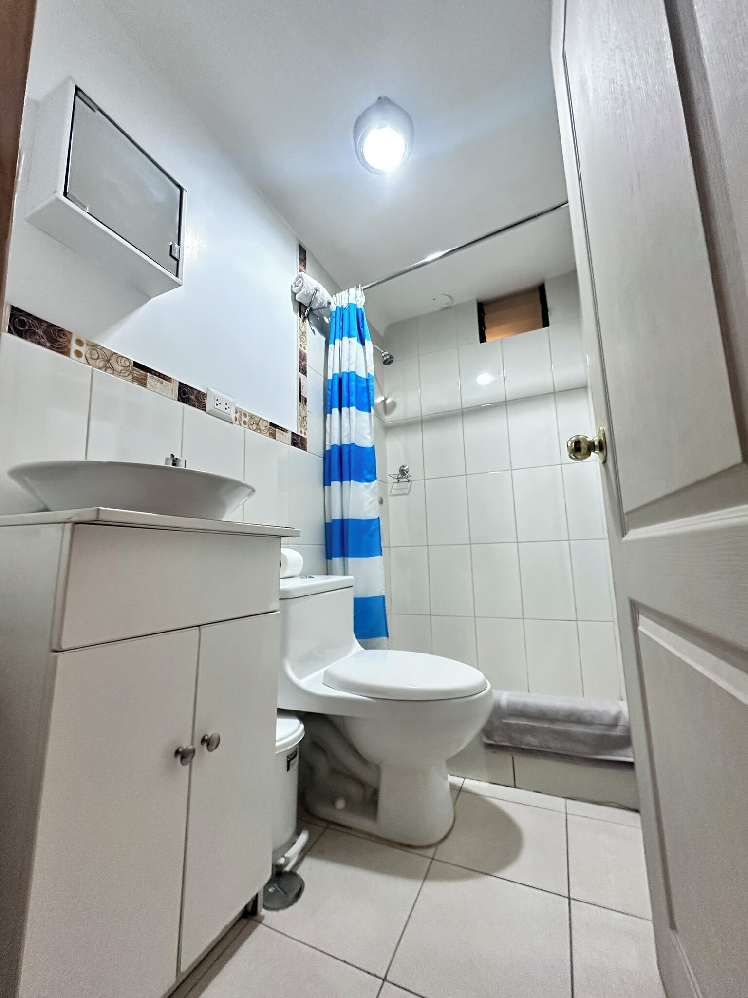 A small bathroom with a toilet, sink, and shower.