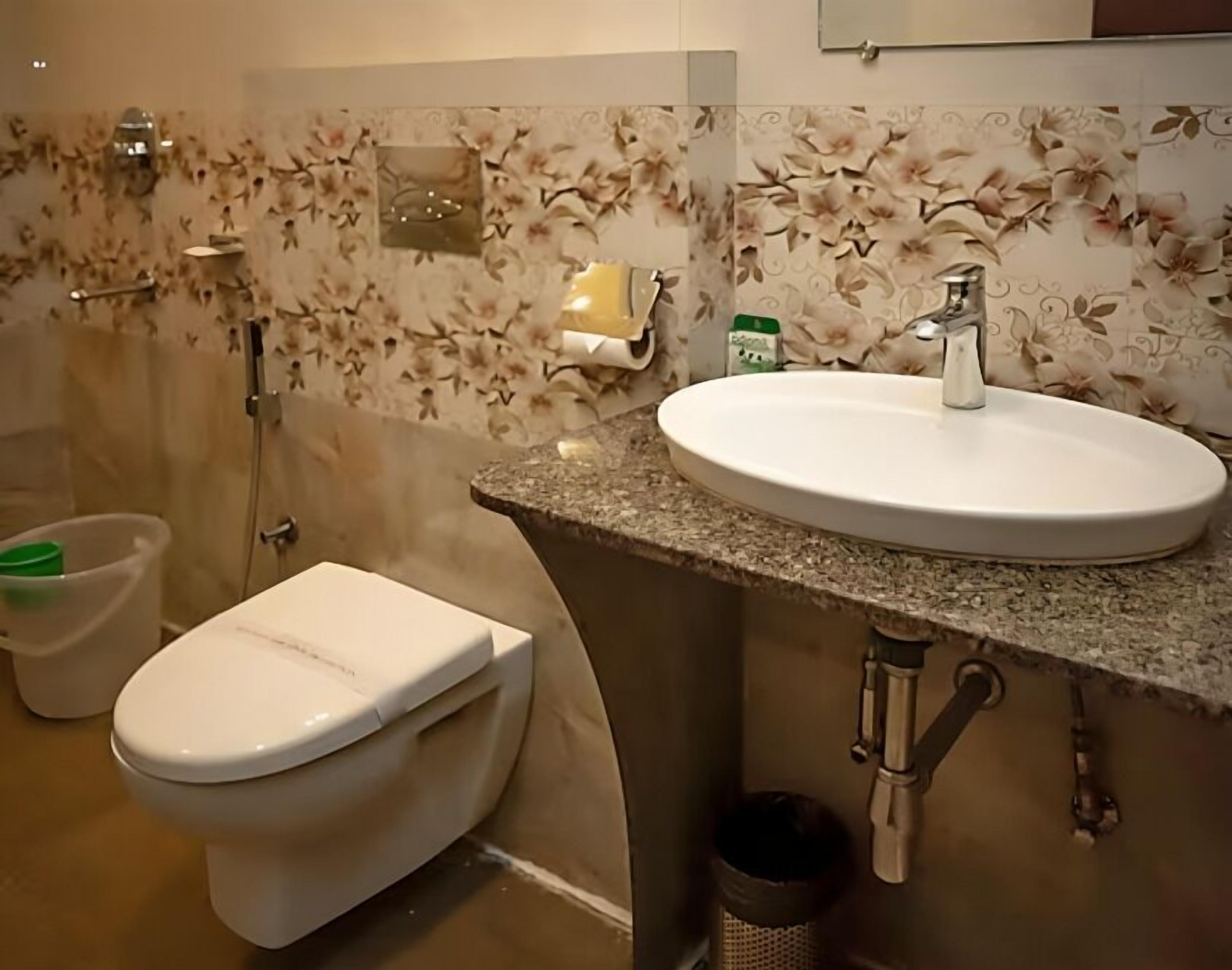 Ein Badezimmer mit Toilette, Waschbecken, Dusche und gefliesten Wänden.