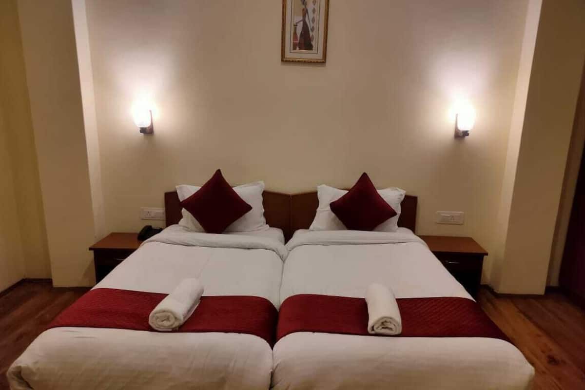 A double bed with red and white bedding, two nightstands, and wall-mounted lights.