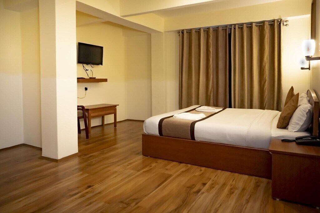 Una habitación de hotel con una cama de madera, un escritorio y una televisión montada en la pared.