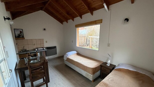 A compact room with a kitchenette, a single bed, and a window providing natural light.