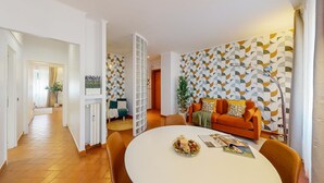 Ein modernes Wohnzimmer mit einem runden Esstisch, einer Couch und einer Wand mit Muster.