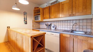 A kitchen with wooden cabinets, a microwave, a sink, and a dishwasher. - Creux de l'ours D172 - 9 guests - Ski in - Ski out (Méribel)