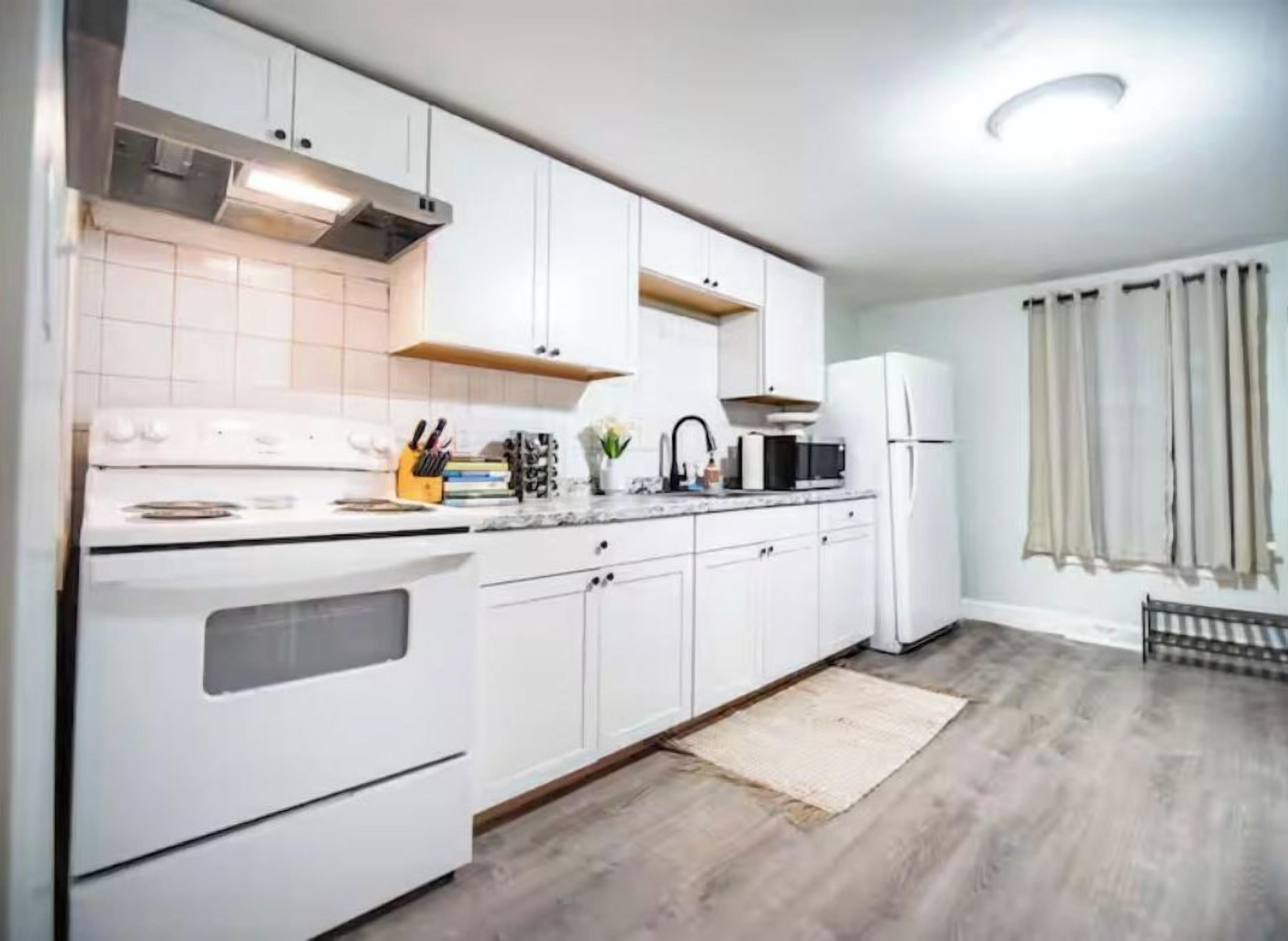 A modern kitchen with white cabinets, a stove, and a microwave.