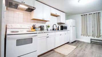 A modern kitchen with white cabinets, a stove, and a microwave.