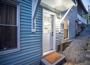A house with a blue siding exterior, a white front door, and a number '122' above the door.