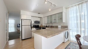 A modern kitchen with a central island, stainless steel appliances, and a view to the living area. - #15 Coastal Heaven Santa Monica (Santa Monica)