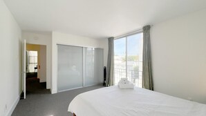 A hotel room with a large bed, a sliding door, a view of the city, and a small table with a lamp. - #15 Coastal Heaven Santa Monica (Santa Monica)