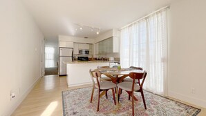 A modern kitchen with white cabinets, a central island, and a dining area with a table and chairs. - #15 Coastal Heaven Santa Monica (Santa Monica)