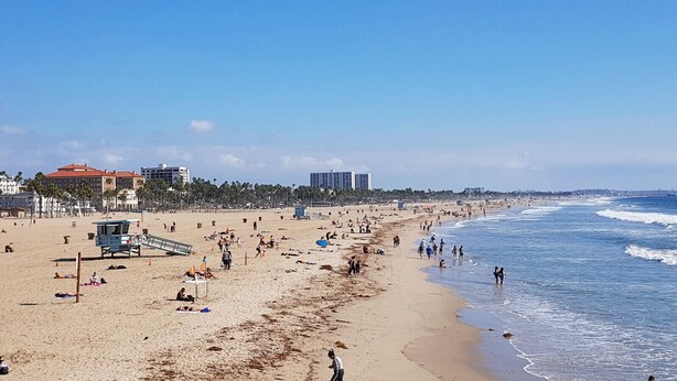 A beach with a lifeguard tower, palm trees, and buildings in the background. - #15 Coastal Heaven Santa Monica (Santa Monica)