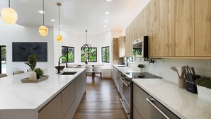 A modern kitchen with a large island, wooden cabinets, and pendant lighting. - Villa Rio Grande 8BR Lazy River Pool + Pickleball (Miami)
