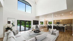 A spacious living area with a large sofa, a coffee table, and a view of the outdoors. - Villa Rio Grande 8BR Lazy River Pool + Pickleball (Miami)