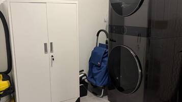 A laundry room with a white cabinet, a large black washing machine, and a blue umbrella.