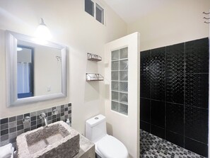 A bathroom with a stone sink, white toilet, and black patterned tiles.