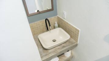 Un baño con un lavabo color beige, un espejo, un perchero y una botella de jabón para manos.