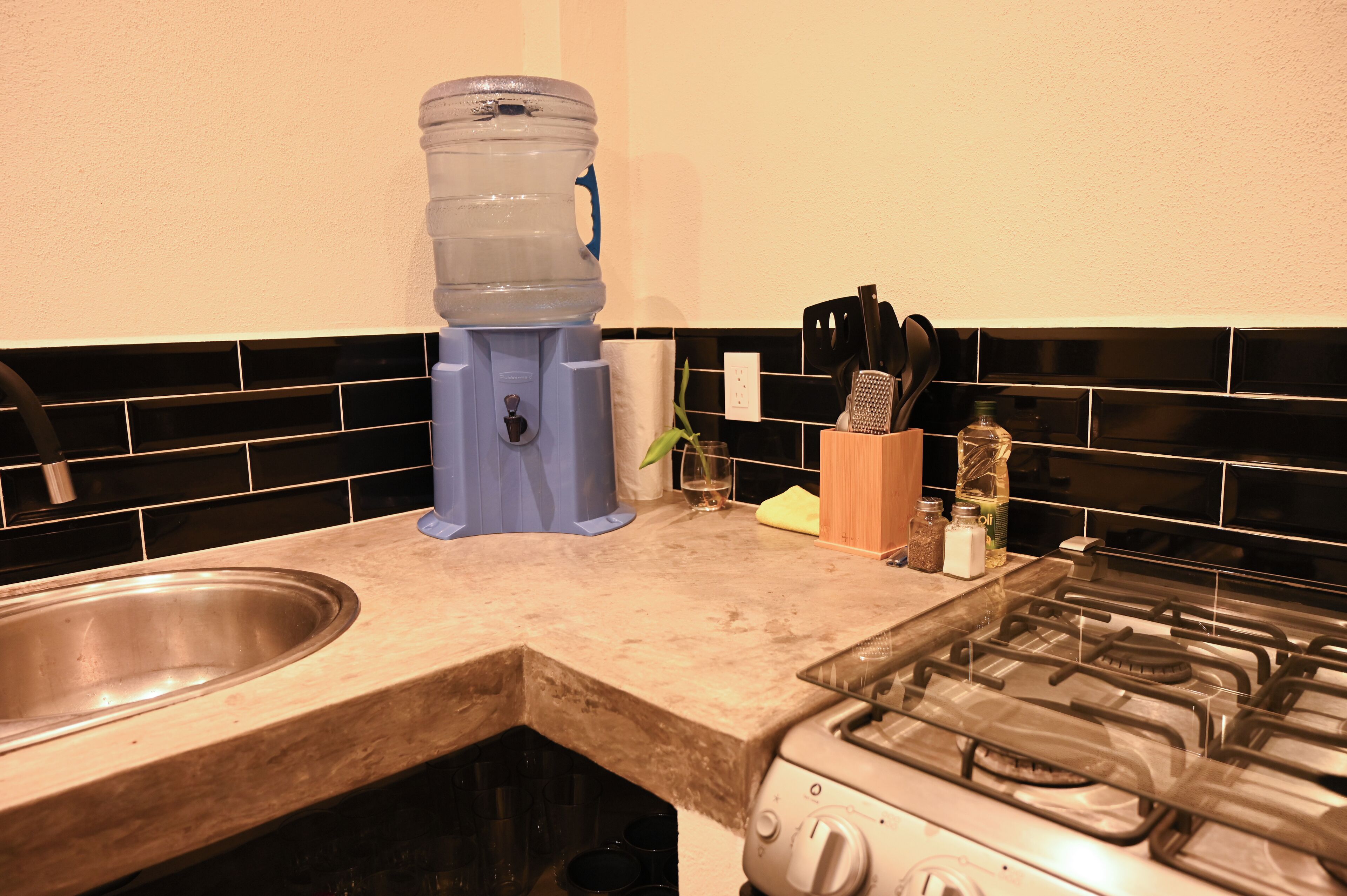 A kitchen with a water dispenser, a sink, a stove, and various kitchen utensils.
