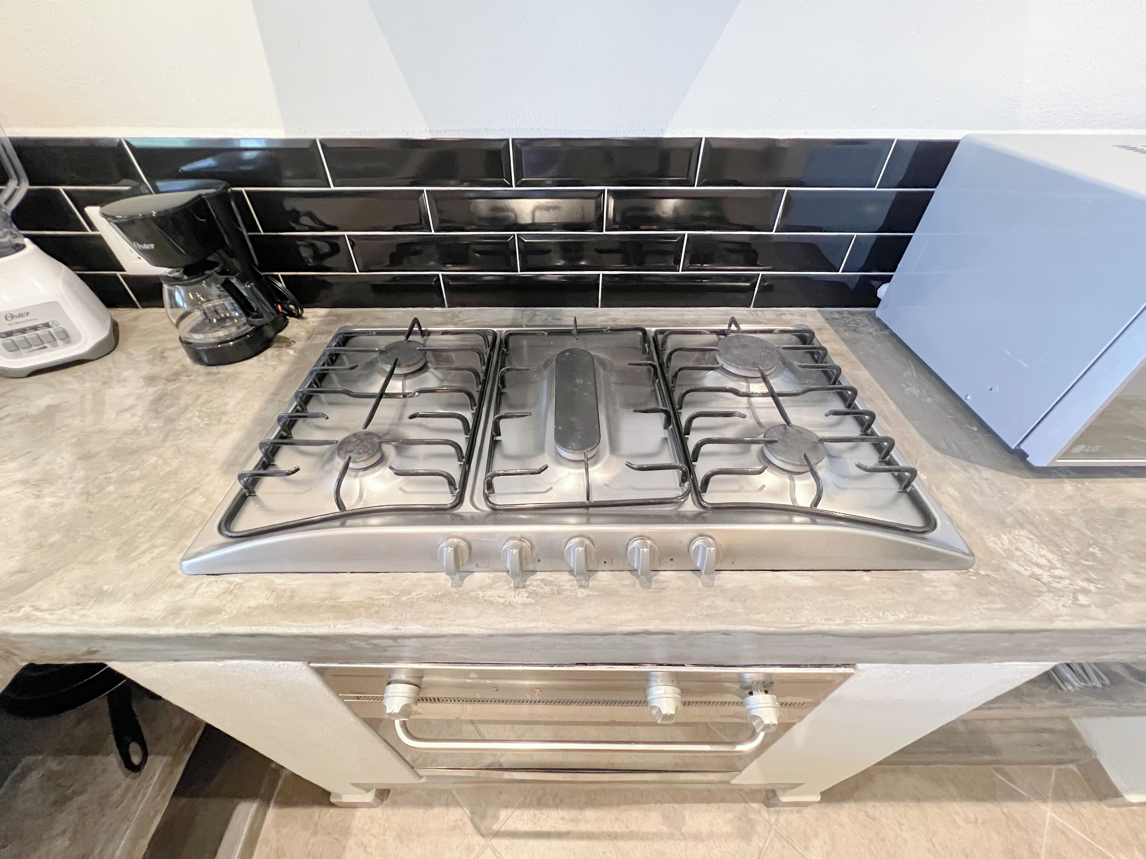 A kitchen with a stainless steel gas stove, a coffee maker, and a blue cabinet.