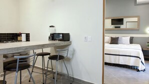 A compact kitchen with a bar area, stools, and a microwave. - Casa Coral (Sayulita)