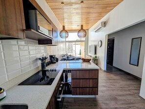Cocina moderna con una isla central, armarios de madera e iluminación colgante.