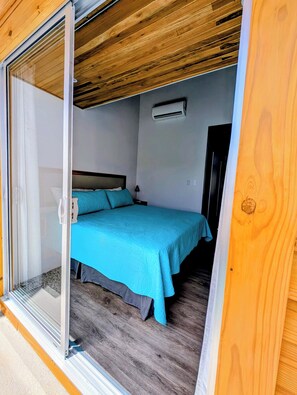 Una habitación con una cama, aire acondicionado y puerta corrediza de vidrio.