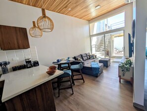 A modern kitchen with wooden cabinets, a white countertop, and hanging pendant lights.