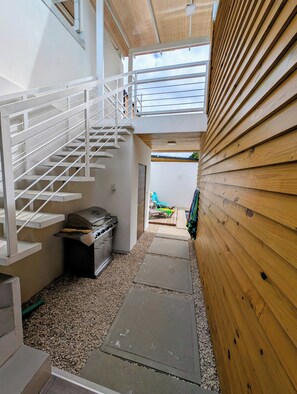 Un espacio interior estrecho con una escalera, una parrilla y vistas a un área exterior.
