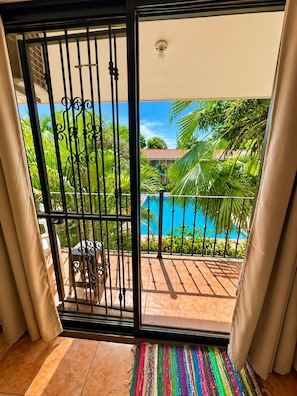 A balcony with a view of a swimming pool and lush greenery.
